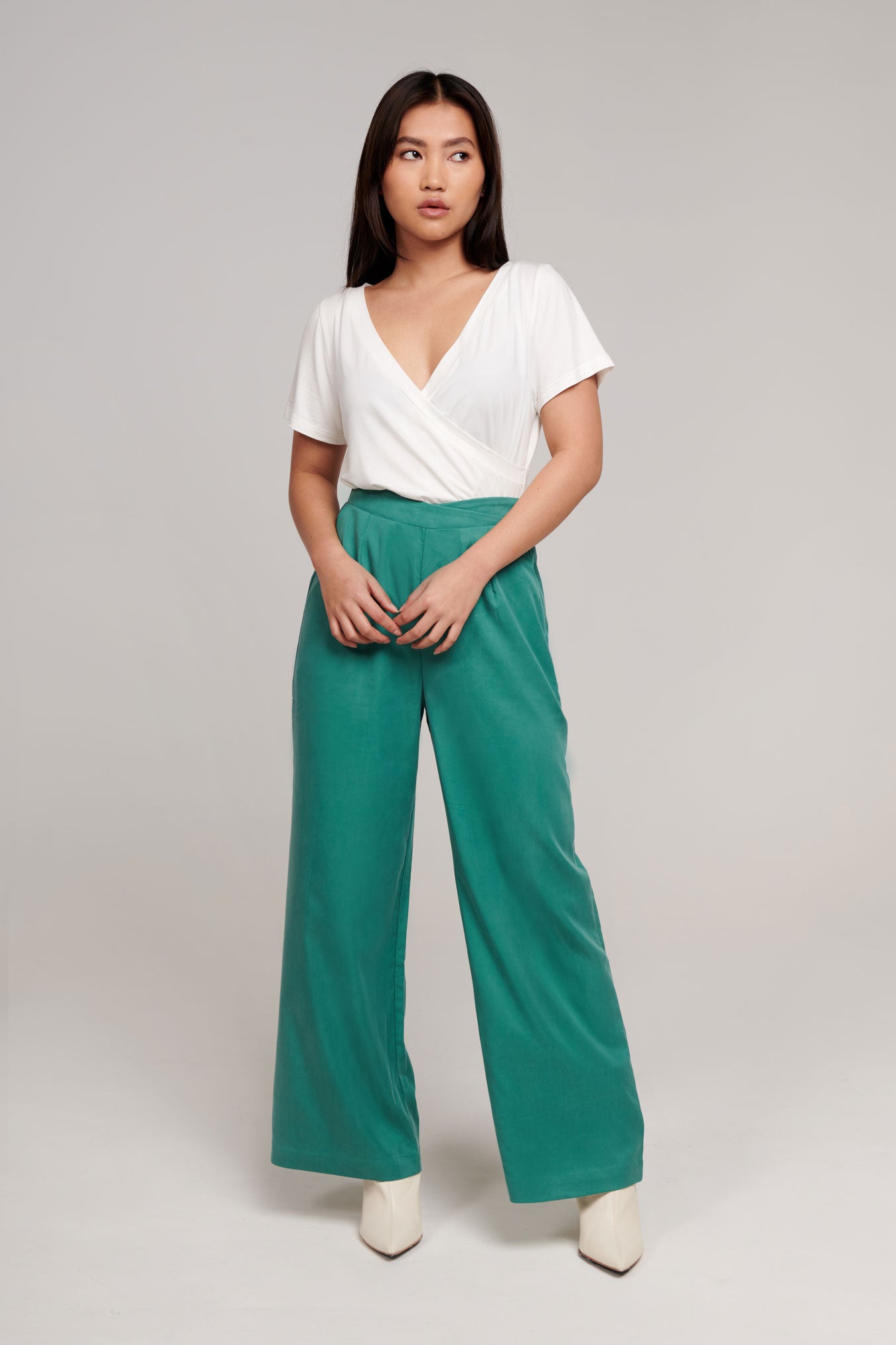 https://ergonaut.co/cdn/shop/products/professional-woman-in-soft-white-modal-wrap-top-and-soft-high-waisted-green-work-pants---2649.jpg?v=1705026692&width=1445
